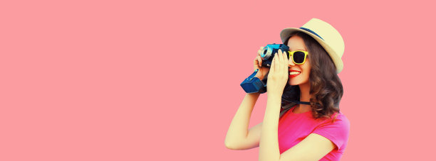 夏天的肖像快乐微笑的年轻女子摄影师与电影相机戴着草帽在粉红色的背景，空白的复制空间为广告文字图片下载
