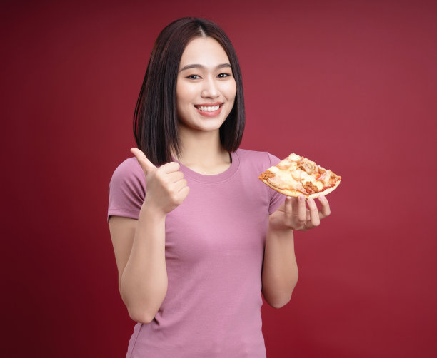 年轻的亚洲女人吃披萨的背景图片下载