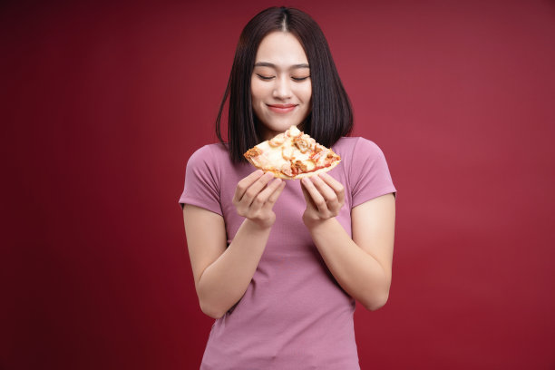 年轻的亚洲女人吃披萨的背景图片下载