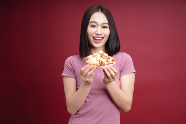 年轻的亚洲女人吃披萨的背景图片下载