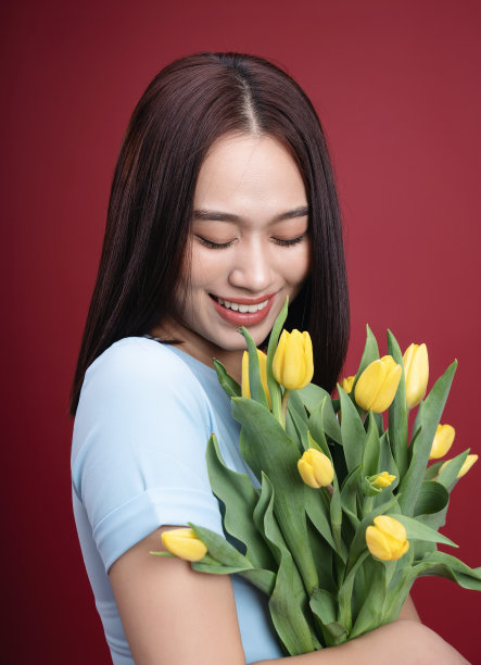 年轻的亚洲妇女拿着郁金香花的背景图像图片下载
