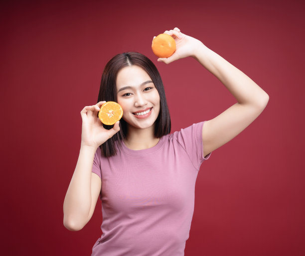 年轻的亚洲女子拿着橙色水果的背景图片下载
