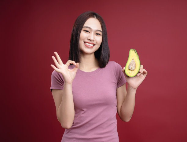 年轻的亚洲女子抱着鳄梨水果的背景图片下载