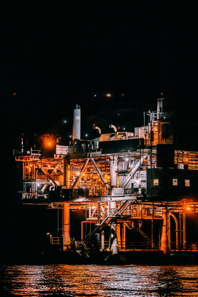 太平洋上一个海上石油钻井平台在黑暗中钻探的长焦镜头图片下载