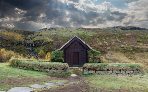 古色古香的维京村庄在湖边的黄金时分日出。橙色色调以中世纪小木屋为特色，以历史悠久的墙纸为背景。古斯堪的纳维亚半岛，群山为背景图片下载