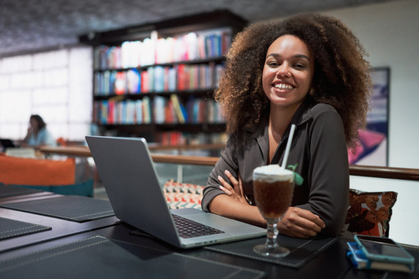 腰画像年轻的黑色巴西爆炸发型的女人在咖啡馆或图书馆工作在她的笔记本电脑图片下载