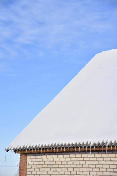 房子的屋顶是白色的雪和蓝色的天空。冬天，房子的屋顶覆盖着雪。有窗户和屋顶上有雪的房子。图片下载