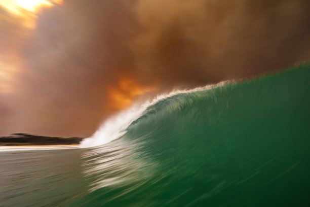 天空中的火，因为浓密的黑烟云形成的丛林火灾反映在海洋表面图片下载