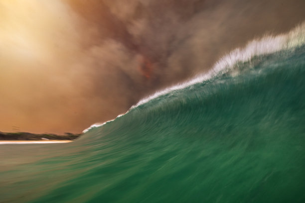 天空中的火，因为浓密的黑烟云形成的丛林火灾反映在海洋表面图片下载