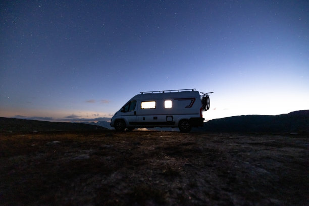 高高原上亮着灯光的露营车，无月星夜图片下载