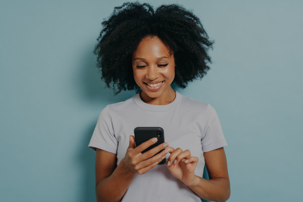 漂亮的卷发女人拿着现代手机，在智能手机设备上输入信息图片下载