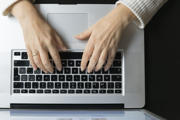 一个女人的手在笔记本电脑上打字的细节图片下载