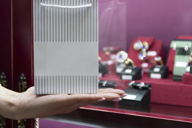 女人手持可印logo的礼品袋在珠宝展示柜前图片下载