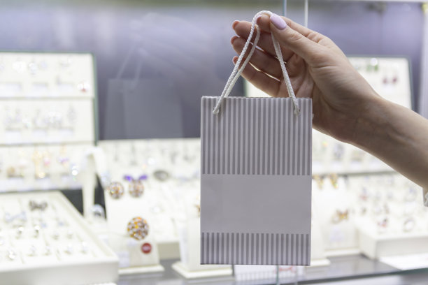 女人手持可印logo的礼品袋在珠宝展示柜前图片下载