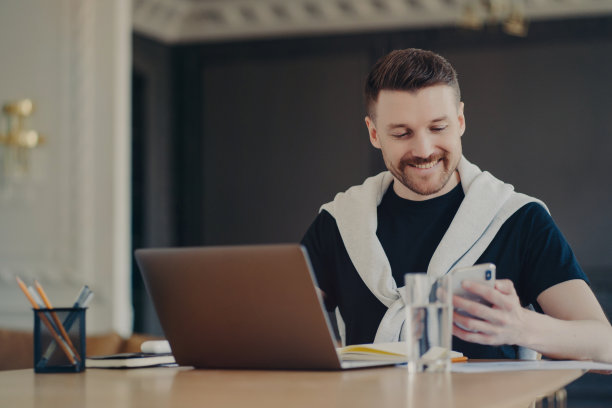 愉快的自由职业者使用移动电话，同时从家里远程工作图片下载