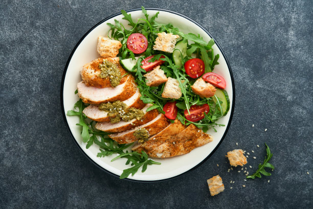 含烤鸡柳、生菜、芝麻菜、菠菜、番茄、黄瓜和香蒜酱的沙拉，配以橄榄油和芝麻图片下载