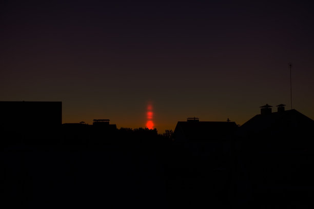 光柱的自然现象。视觉大气现象，光学效果，太阳在日落时在空气中折射。屋顶上美丽的日落天空。横幅、海报图片下载