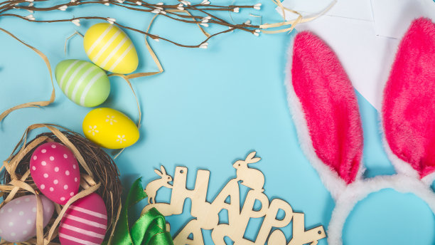 祝贺明信片与复活节彩蛋的蓝色背景和兔子耳朵和地方的文字顶部视图图片下载