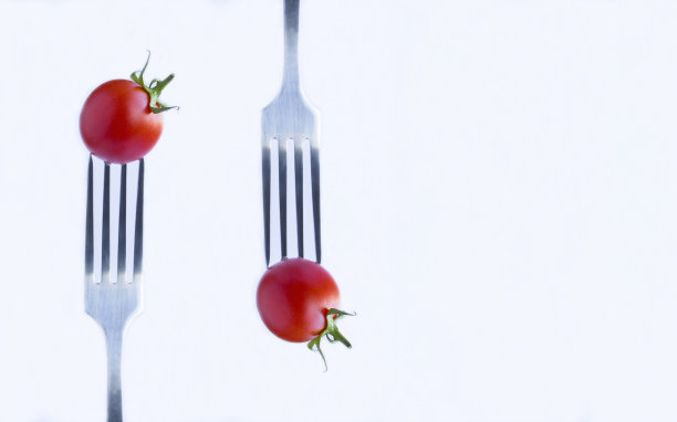 樱桃番茄插在白色背景的银叉上。特写镜头。副本的空间。图片下载