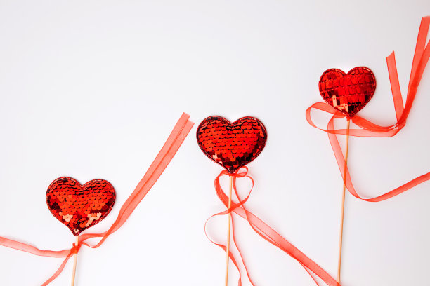 白色背景上镶着亮片的红心。情人节背景图片下载