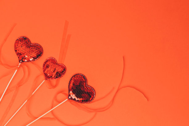 红色背景上镶着亮片的红心。情人节的背景。平躺图片下载