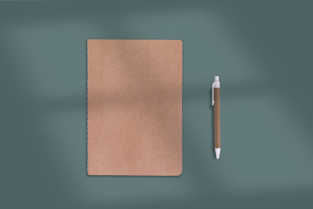 笔记本和笔由回收材料制成，绿色背景和窗帘。图片下载