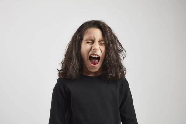 一个长头发的小男孩在白色背景下尖叫。图片下载