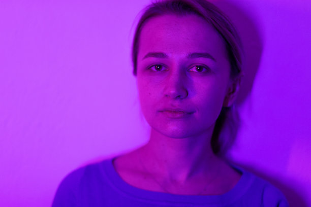 女性肖像在室内采用霓虹灯色，人用紫色、蓝色、红色和粉红色的灯光。女性照片，生活方式概念摄影与多色灯和颜色。图片下载