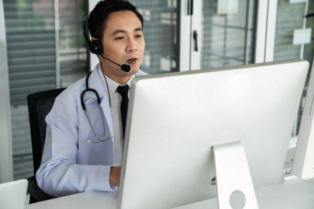 医生戴着耳机在诊所或医院积极视频通话。远程保健和远程医疗服务的概念。图片下载