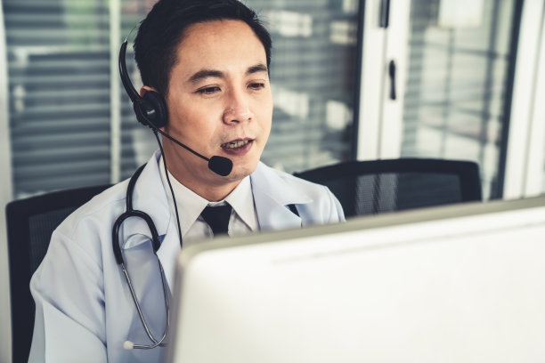 医生戴着耳机在诊所或医院积极视频通话。远程保健和远程医疗服务的概念。图片下载
