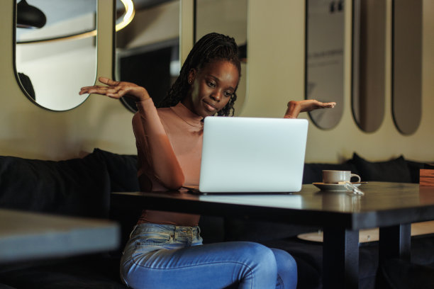 困惑的多种族妇女喝咖啡，用笔记本电脑工作，在咖啡馆，举手。远程工作问题，不知道图片下载