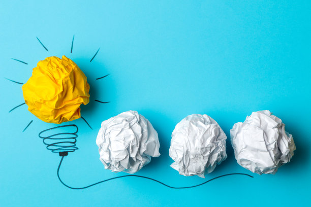 概念创意。创意的概念。揉皱的纸球和彩绘灯泡在明亮的背景。比喻,灵感。图片下载