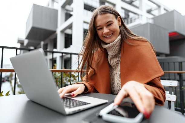 年轻女子工作与她的笔记本电脑坐在桌子在街上图片下载