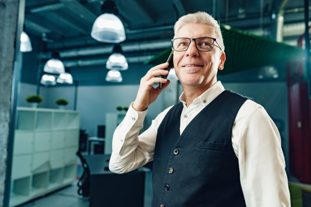 英俊成熟的商人在办公室打电话图片下载