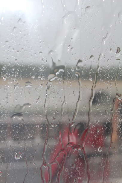 飞机窗户上的雨滴特写，背景是模糊的围裙。图片下载