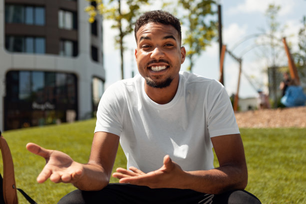 快乐的非裔美国人做视频电话和手势，同时对着摄像机说话，坐在市区的户外图片下载