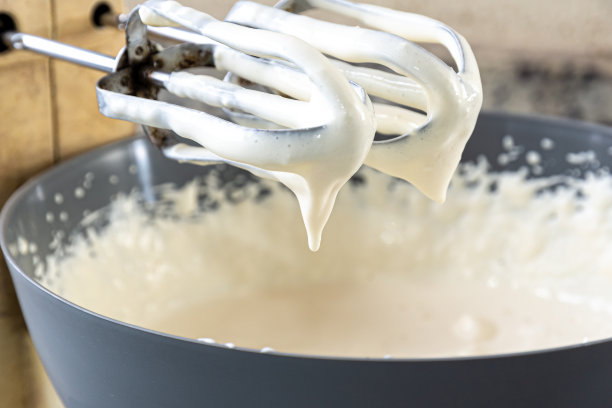 电动搅拌器的一部分装有乳酪蛋糕准备用的奶油。图片下载