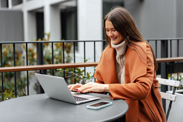 年轻女子工作与她的笔记本电脑坐在桌子在街上图片下载
