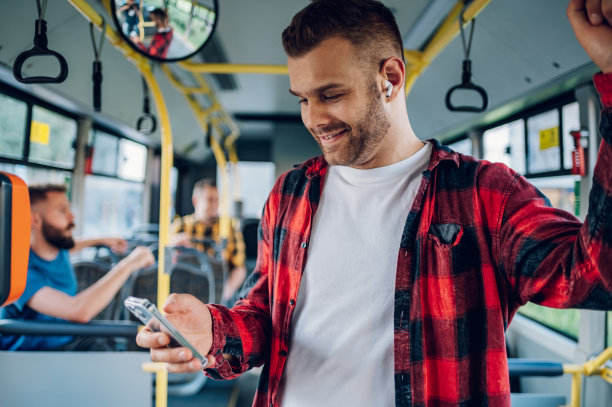一名男子在乘坐公交车时使用智能手机图片下载