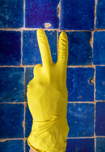 手在手套显示胜利的标志，V符号与手指在旧脏瓷砖墙图片下载