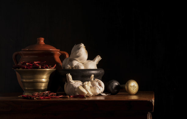 静物画的干红辣椒，辣椒和大蒜与杵和臼在黑色背景图片下载