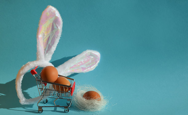鸡蛋在购物车里，购物和兔子耳朵。复活节快乐。为春节做准备。图片下载