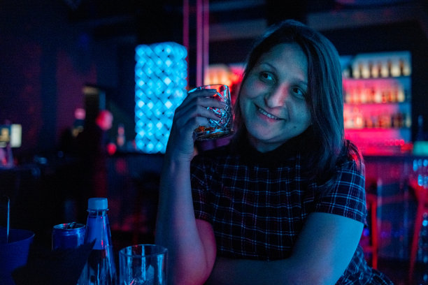 年轻快乐的女人与玻璃杯在夜总会。图片下载