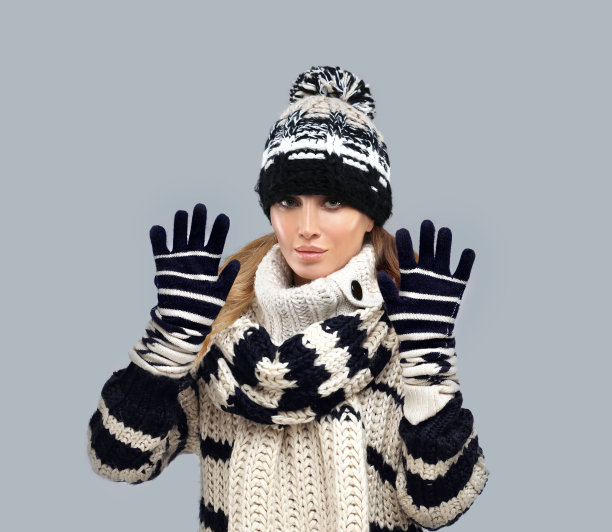 冬天的肖像，一个美丽的年轻女子穿着毛衣对蓝色背景摆姿势。图片下载