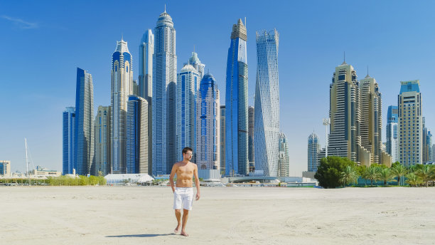 一名年轻男子在迪拜的海滩上游泳，阿拉伯联合酋长国迪拜朱美拉海滩图片下载