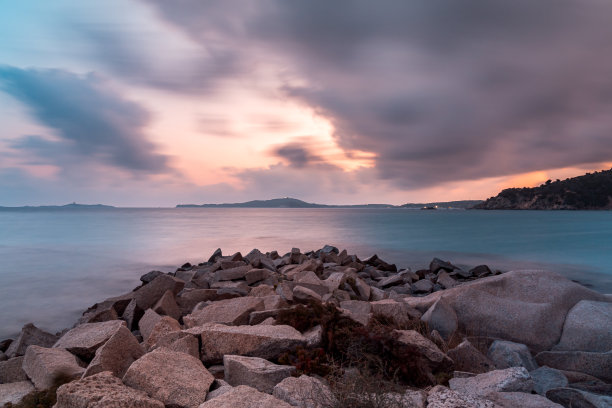 维拉西米乌斯蓬塔莫伦蒂斯海滩上的岩石上的长时间曝光日落视图，有戏剧性的云层和红色的火焰天空图片下载