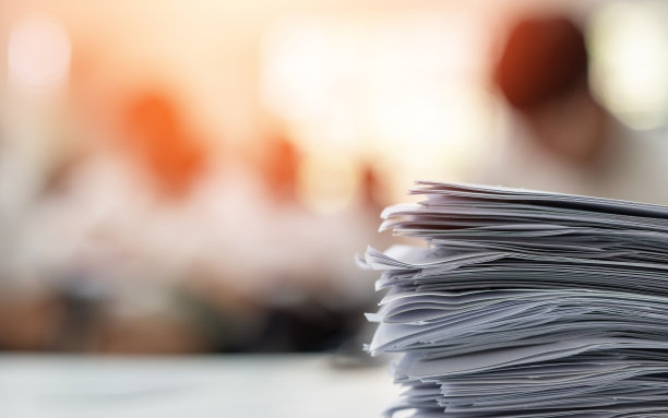 考试答卷堆，模糊的申请文件文书堆在办公室工作台上的考场或教室与模糊的教育背景学校班大学生参加考试图片下载