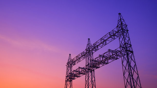 在色彩缤纷的黄昏天空背景下，未与在建新电站电缆连线的高压钢电塔剪影图片下载