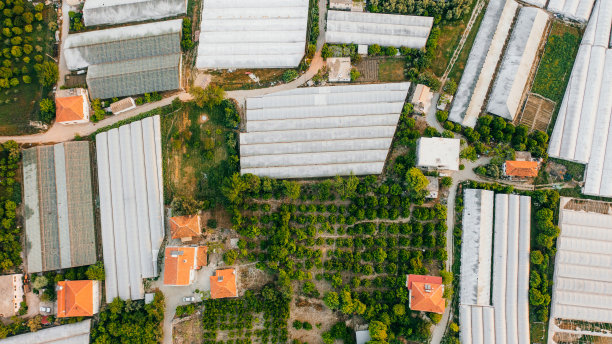 鸟瞰农场温室在广阔的土地上，在风景如画的日落在土耳其图片下载