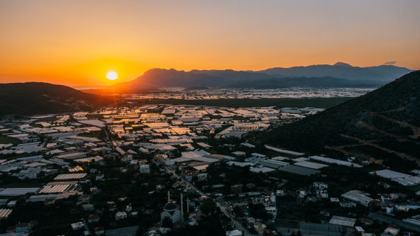 鸟瞰农场温室在广阔的土地上，在风景如画的日落在土耳其海上图片下载